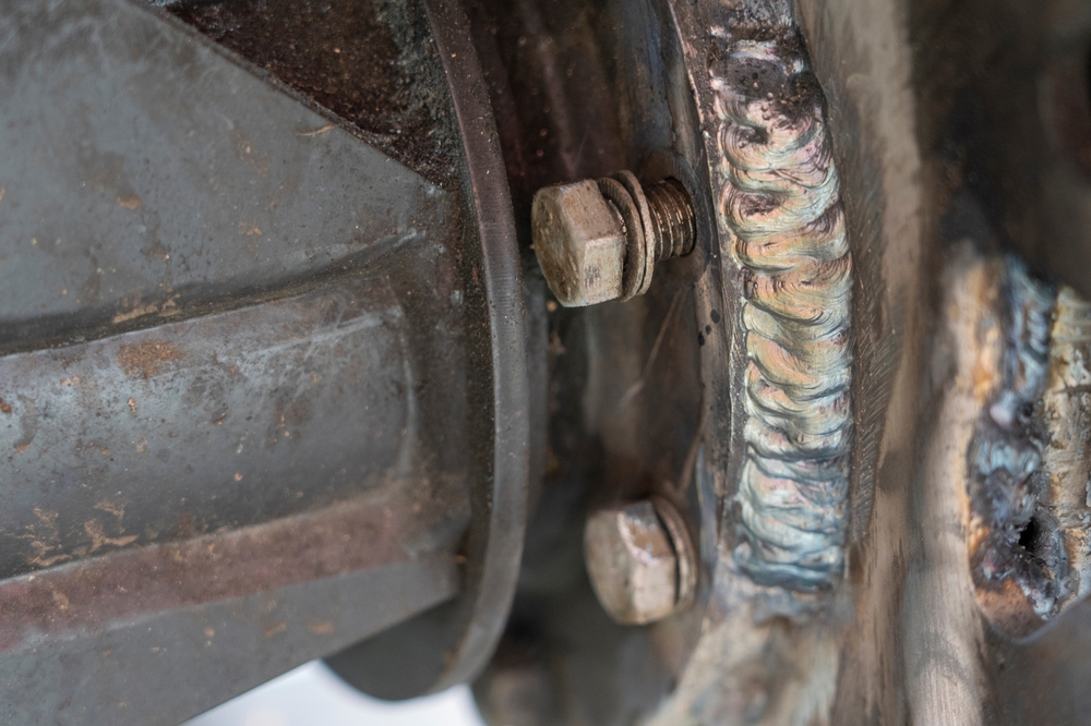 Close-up view of a welded joint on a metal structure, showcasing the precision of the welding work and the bolts securing the assembly.